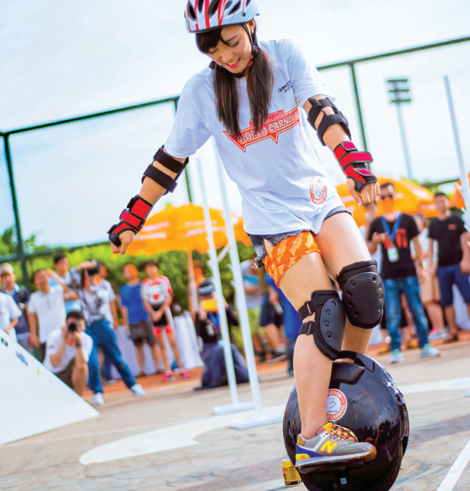 Person on a unicycle without pedals while a crowd watches on
