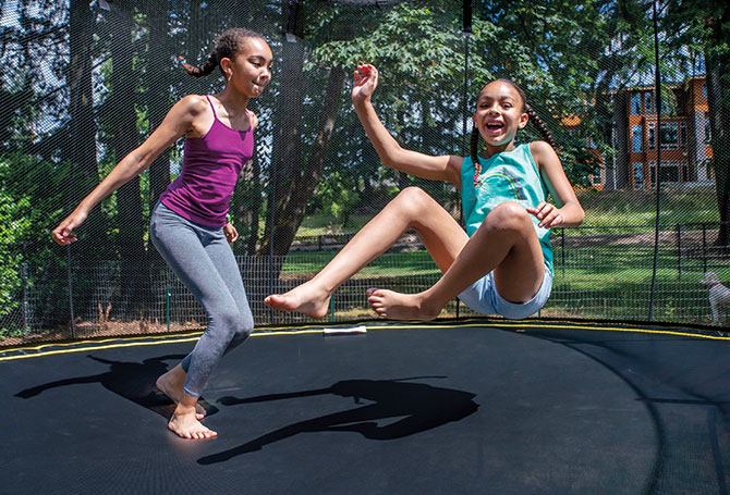 Two girls jumping on a trampoline