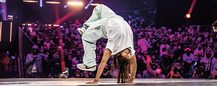 Image of a person break dancing on a stage in front of an audience