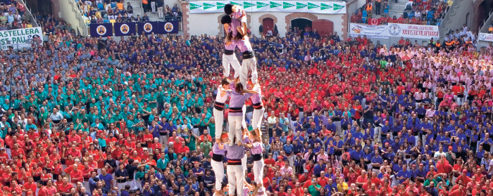 Photo of a huge crowd gathered in matching shirts to watch a human tower