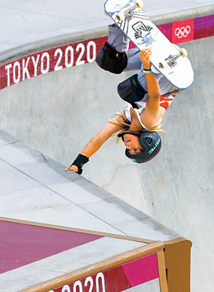 Photo of a female skateboarding performing a move where she&apos;s upside down